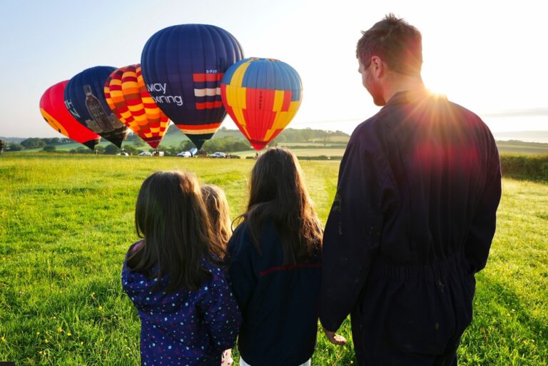 Kids with their father looking at Hot Air Balloons in a sunny field